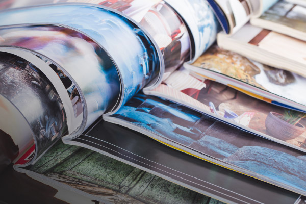 Printed magazines opened at the center and pile on top of each other.